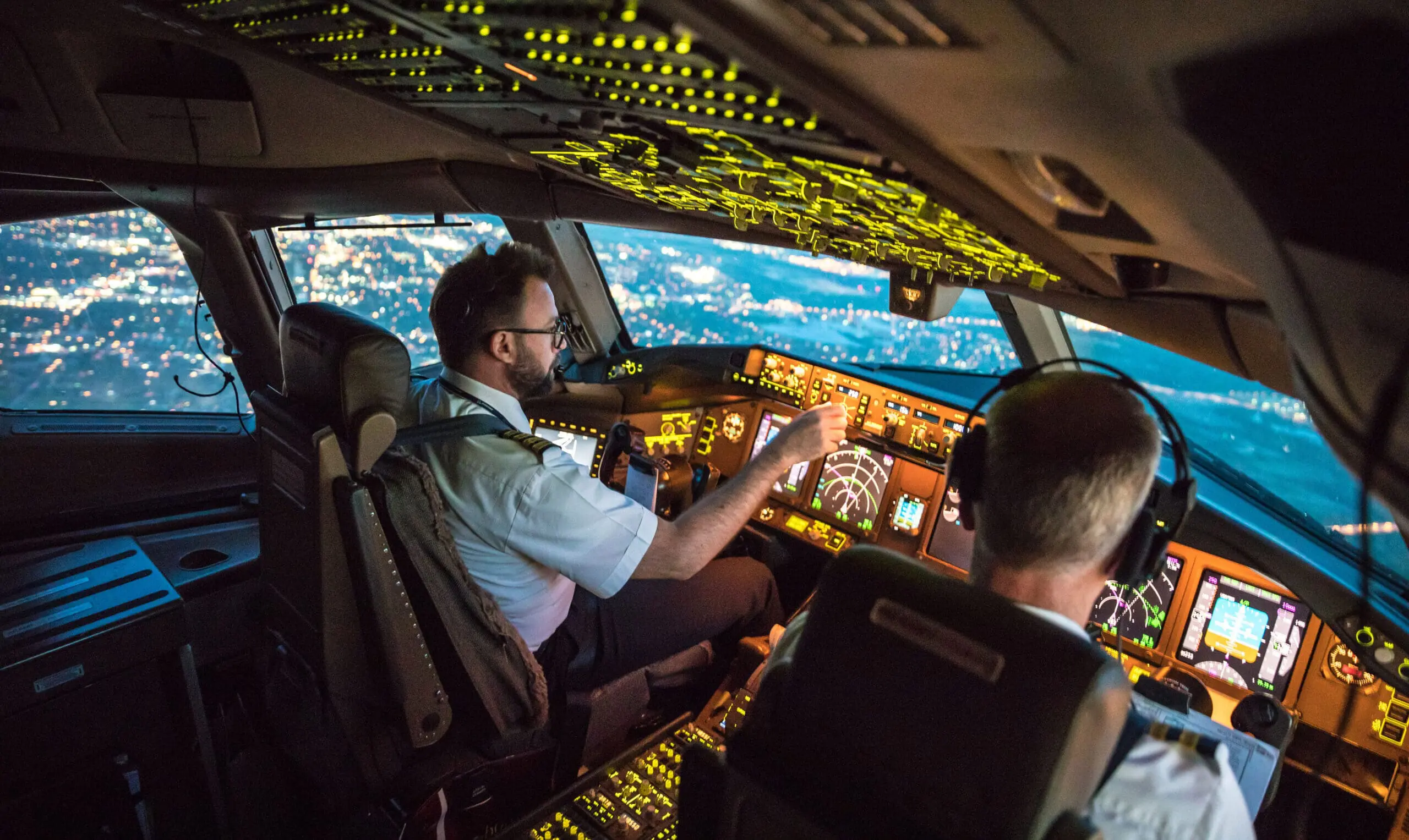Two pilots at work during departure. The view from the flight deck with high workload the beginning night through the wind shield
